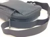 A close-up view of a black messenger bag with its strap in the foreground. Náhľad obrázku produktu