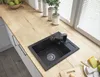 A kitchen counter with a black sink and faucet, along with some decorative items and food. Anteprima dell’immagine prodotto