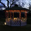 A gazebo decorated with Christmas lights and candles at dusk. Produktbild-Vorschau