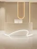A modern reception desk with curved lines and integrated lighting in a neutral-toned room. Voir les images du produit