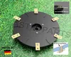 A black rotary cutter blade with gold blades on a grassy background. Náhled obrázku produktu