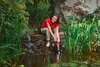 A woman is using a submersible pump in a garden pond. Náhled obrázku produktu