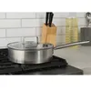 A stainless steel pot with a glass lid sits on a stovetop. Náhľad obrázku produktu
