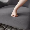 A hand is pressing into the soft, gray fabric of a chair cushion. Náhled obrázku produktu