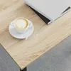 A close-up view of a coffee cup with latte art and a spoon on a wooden table, with books in the background. Voir les images du produit