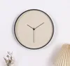 A minimalist wall clock with a beige face and black frame, mounted on a white wall. Anteprima dell’immagine prodotto
