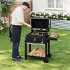 A man is grilling food on a charcoal grill in a backyard setting. Produktbild-Vorschau