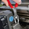A hand is using a pair of pliers to grip a bolt on a piece of machinery. Voir les images du produit