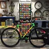 A bicycle painted with colorful spray paint is displayed in a workshop with shelves of spray paint cans in the background. Produktbild-Vorschau