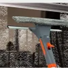 Grauer und oranger Fensterabzieher mit Mikrofaserschrubber reinigt ein mit Wassertropfen bedecktes Fenster Anteprima dell’immagine prodotto