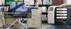 A portable air conditioner is shown in a home office setting next to a desk and chair. Produktbild-Vorschau