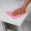 A hand with pink nail polish is wiping a white high-gloss table with a pink cloth. Produktbild-Vorschau