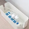 A white cable management box containing a power strip with several plugs and adapters. Anteprima dell’immagine prodotto