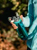 A person holding a blue water bottle outdoors. Anteprima dell’immagine prodotto