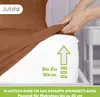 A hand is stretching a brown fitted sheet over a white mattress. Produktbild-Vorschau