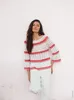 A woman wearing a crochet sweater and white pants, standing against a textured wall. Produktbild-Vorschau