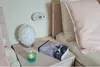 A bedside table with a carbon monoxide detector, a lamp, a candle, and a book. Podgląd zdjęcia produktu