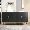 A black sideboard with geometric patterns and gold accents is displayed in a room with a framed picture and a lamp. Produktbild-Vorschau