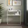 A white console table with decorative items and books, placed in a room with artwork on the wall and a plant. Náhled obrázku produktu