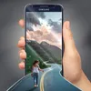 A hand holding a smartphone displaying a scenic road with a person walking away from the viewer. Produktbild-Vorschau