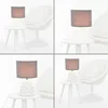 A collage of four images showing a table lamp with a brown shade and a white base, placed on a small white side table next to a white armchair. Produktbild-Vorschau
