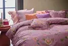 A bed with multiple pillows and a comforter, all featuring a floral and striped pattern. Produktbild-Vorschau