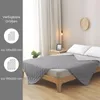 A bedroom scene with a bed covered by a quilted blanket. Produktbild-Vorschau