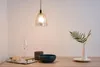 A pendant light hangs above a table set with a wine glass, a decorative bowl, and a vase with greenery. Anteprima dell’immagine prodotto