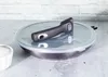 A frying pan with a glass lid and a detachable handle is placed on a countertop. Podgląd zdjęcia produktu