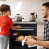 A father and son are in a kitchen, with the son operating the oven and the father holding a tray of freshly baked croissants. Produktbild-Vorschau