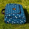 A folded picnic blanket with a polka dot pattern lies on green grass. Náhled obrázku produktu
