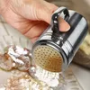 A hand is using a stainless steel shaker to dust flour onto shrimp. Produktbild-Vorschau