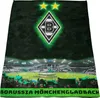 A blanket with the Borussia Mönchengladbach logo and stadium scene, displayed with fans holding flags. Produktbild-Vorschau