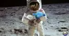 An astronaut on the moon holding plush toys of Earth and a white creature. Produktbild-Vorschau