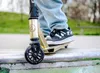 A person's legs and feet are shown on a scooter in a skate park. Produktbild-Vorschau