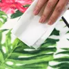 A hand is wiping a blanket with a white cloth. The blanket has a floral and leaf pattern. Náhled obrázku produktu