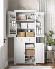 A white storage cabinet filled with various bathroom and home goods, with a potted plant to the right. Náhled obrázku produktu