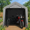 A grey fabric storage tent with a bicycle and a red motorcycle inside, set in a garden with flowers and trees. Náhled obrázku produktu