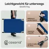 A person is holding a folded blue camping cot. The image also features close-ups of the product's features with descriptive text. Produktbild-Vorschau