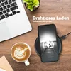 A desk scene with a laptop, coffee, and a phone charging wirelessly. Produktbild-Vorschau
