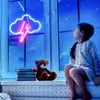 A young girl sits on a windowsill at night, looking out at a neon cloud and lightning bolt sign in the window. A teddy bear and books are on the windowsill. Náhled obrázku produktu