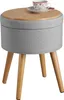 A round ottoman with a wooden lid and fabric upholstery, resting on three wooden legs. A cup and saucer are on the lid. Podgląd zdjęcia produktu
