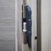 A close-up view of a door hinge with a specialized tool attached, designed for door installation. Produktbild-Vorschau