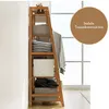A wooden ladder shelf filled with storage boxes and folded clothes, standing against a wall next to a window. Produktbild-Vorschau