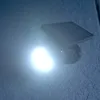 A solar-powered LED light with a motion sensor is mounted on a textured wall. Produktbild-Vorschau
