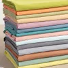 A stack of folded fabric sheets in various pastel colors. Produktbild-Vorschau