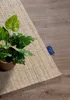 A close-up of a rug with a potted plant on it, placed on a wooden floor. Podgląd zdjęcia produktu