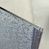 Close-up of a textured glass edge with a silver metal trim. Produktbild-Vorschau