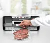 A person is using a vacuum sealer machine to seal a bag of meat on a countertop in a kitchen. Produktbild-Vorschau