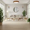 A modern living room with a sofa, chairs, coffee table, and plants, illuminated by a ceiling light. Produktbild-Vorschau